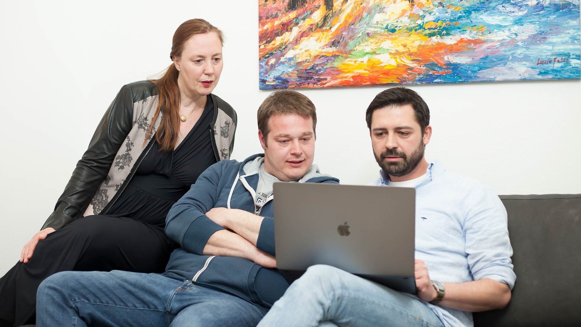 Drei Mitarbeitende von mindmelt schauen gemeinsam in einen Laptop